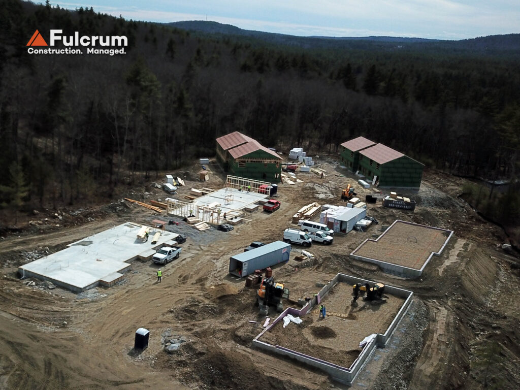 Drone view of Brookline Woods housing development showing sitework, foundations, and multiple buildings under construction