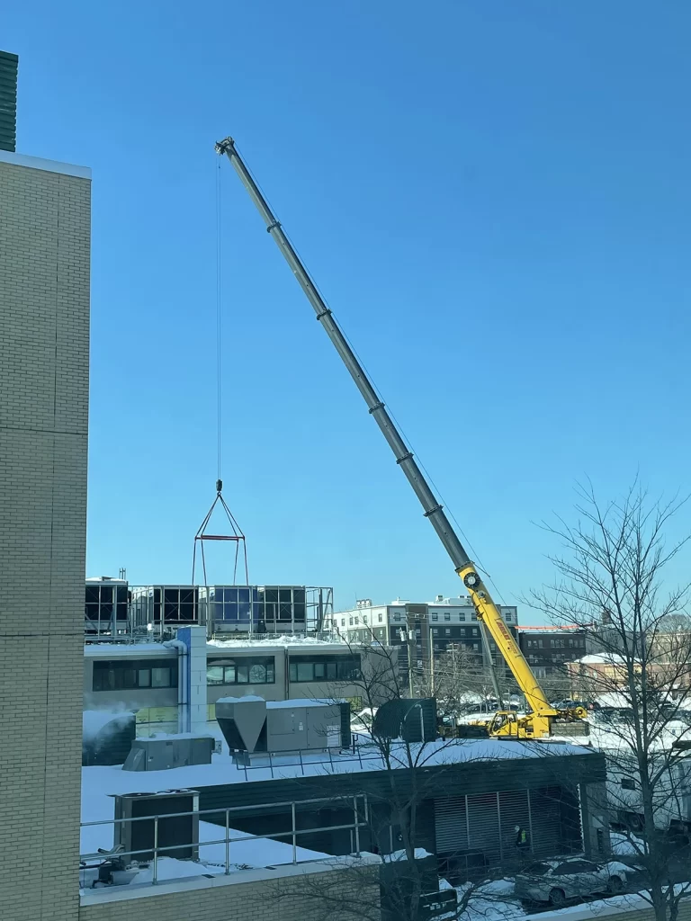 Crane lifting HVAC equipment onto roof at Southern NH Medical Center renovation project