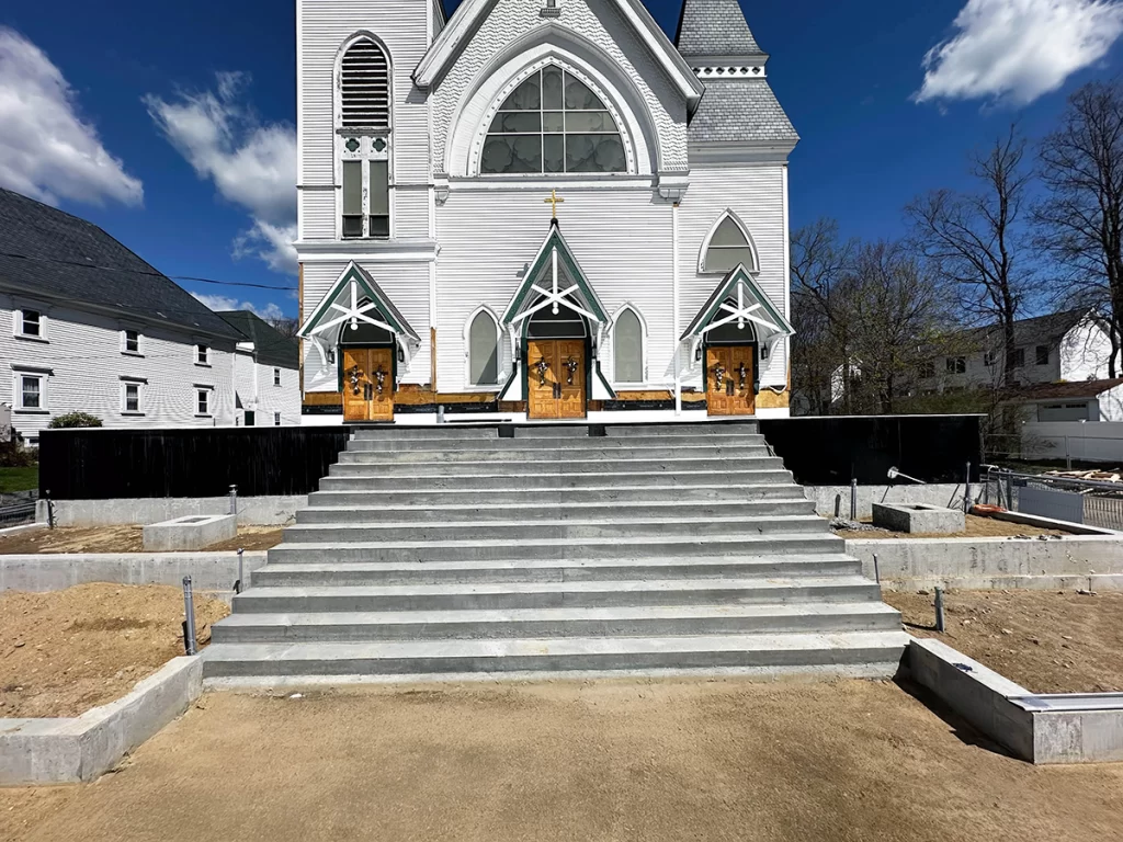 Construction progress at Saint Patrick Roman Catholic Church showing concrete entry sequence and sitework