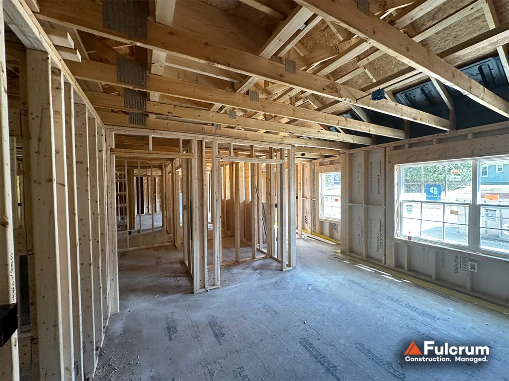 Interior construction at Pelham Terrace in Pelham, NH, showing wood-framed walls, roof trusses, and residential spaces being prepared for mechanical, electrical, and plumbing installations.