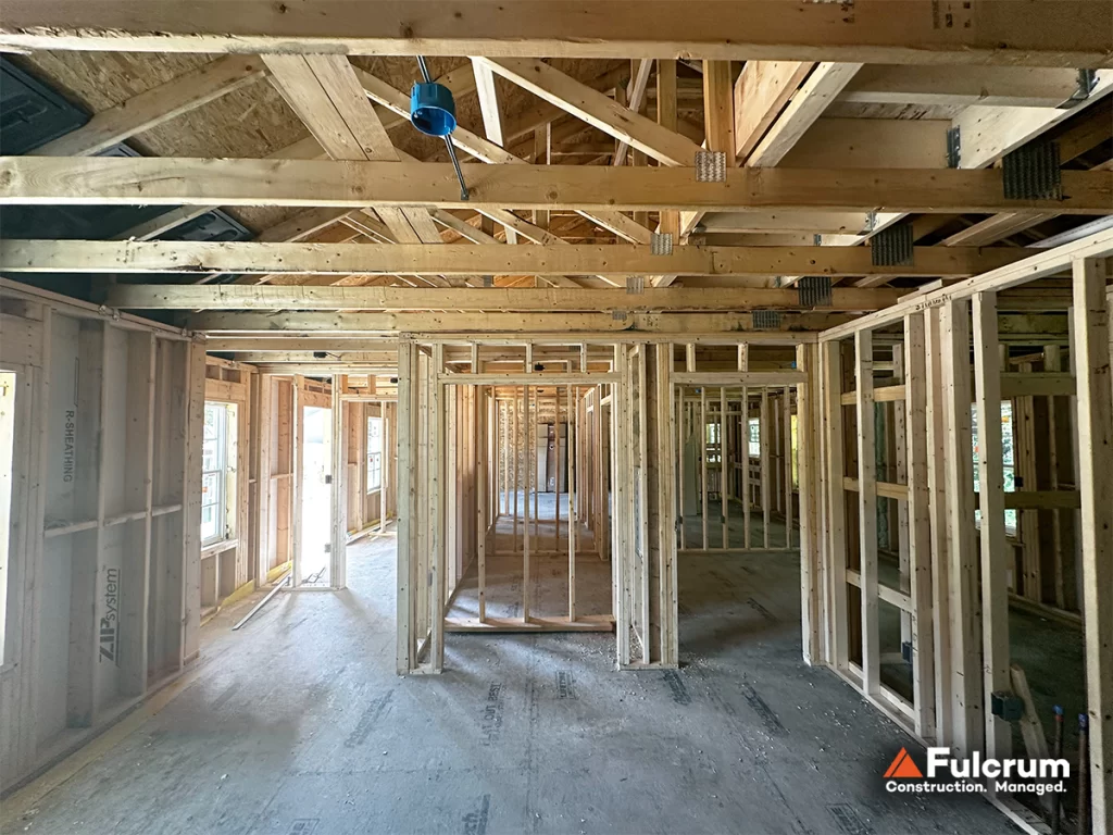 Interior view of the Pelham Terrace six-unit residential building showing wood-framed room partitions, exposed ceiling trusses, and electrical rough-in components.