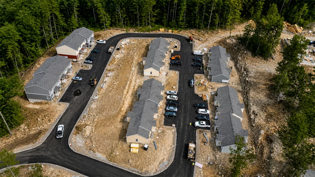 Aerial drone view of Brookline Woods in Brookline, NH, showing newly constructed workforce housing buildings, paved access roads, and ongoing site improvements.