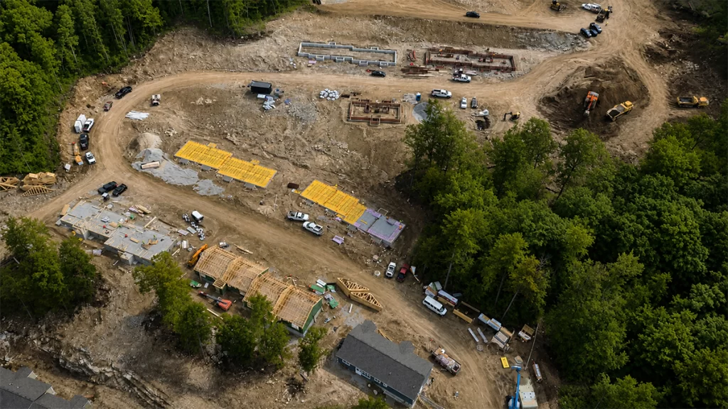 Aerial drone view of Phase II construction at Brookline Woods in Brookline, NH, showing new senior housing foundations, wood framing, and active site development.